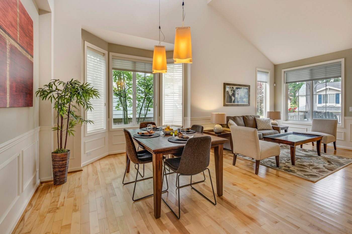 A dining table set in a room with tall windows and a sofa beyond